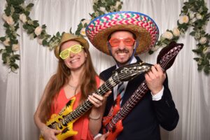 Paar in der Fotobox mit Sombrero und zwei Luftgitarren