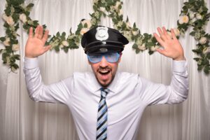 Gast in der Fotobox mit Polizeimütze und Partybrille