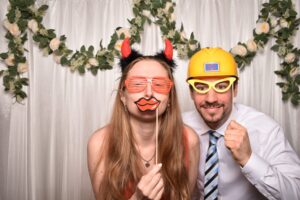 Paar in der Fotobox mit Teufelshörnern, Bauhelm und Partybrillen