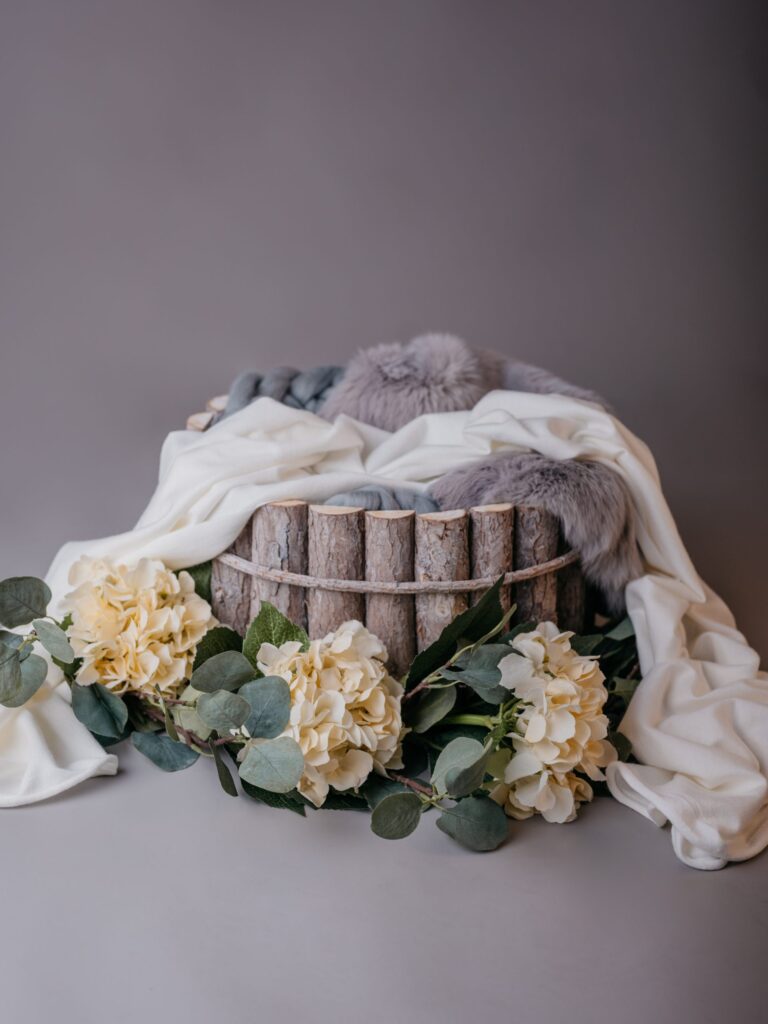 Set im Fotostudio in Denkendorf: Holzkorb mit grauem Fell, cremefarbenem Tuch und weißen Hortensien